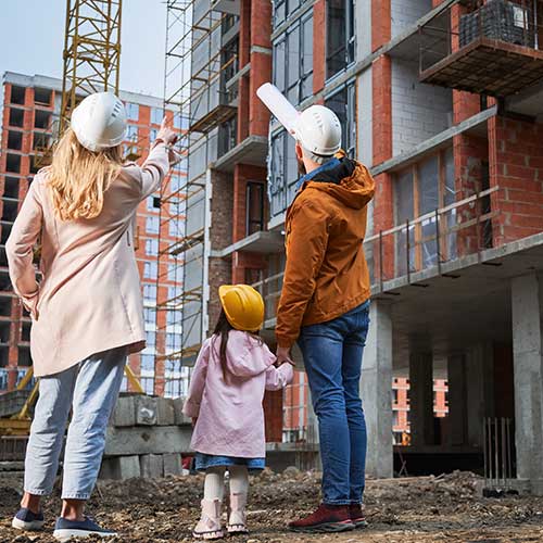 man, woman and a child looking at a tall block of flats being developed