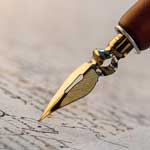 Close up of a gold tipped calligraphy pen writing calligraphy