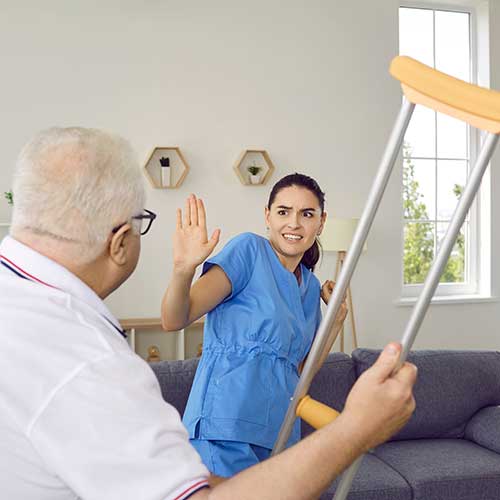 Older man waving a metal crutch at a nurse